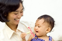 Mother smiling with her child while playing with a flower