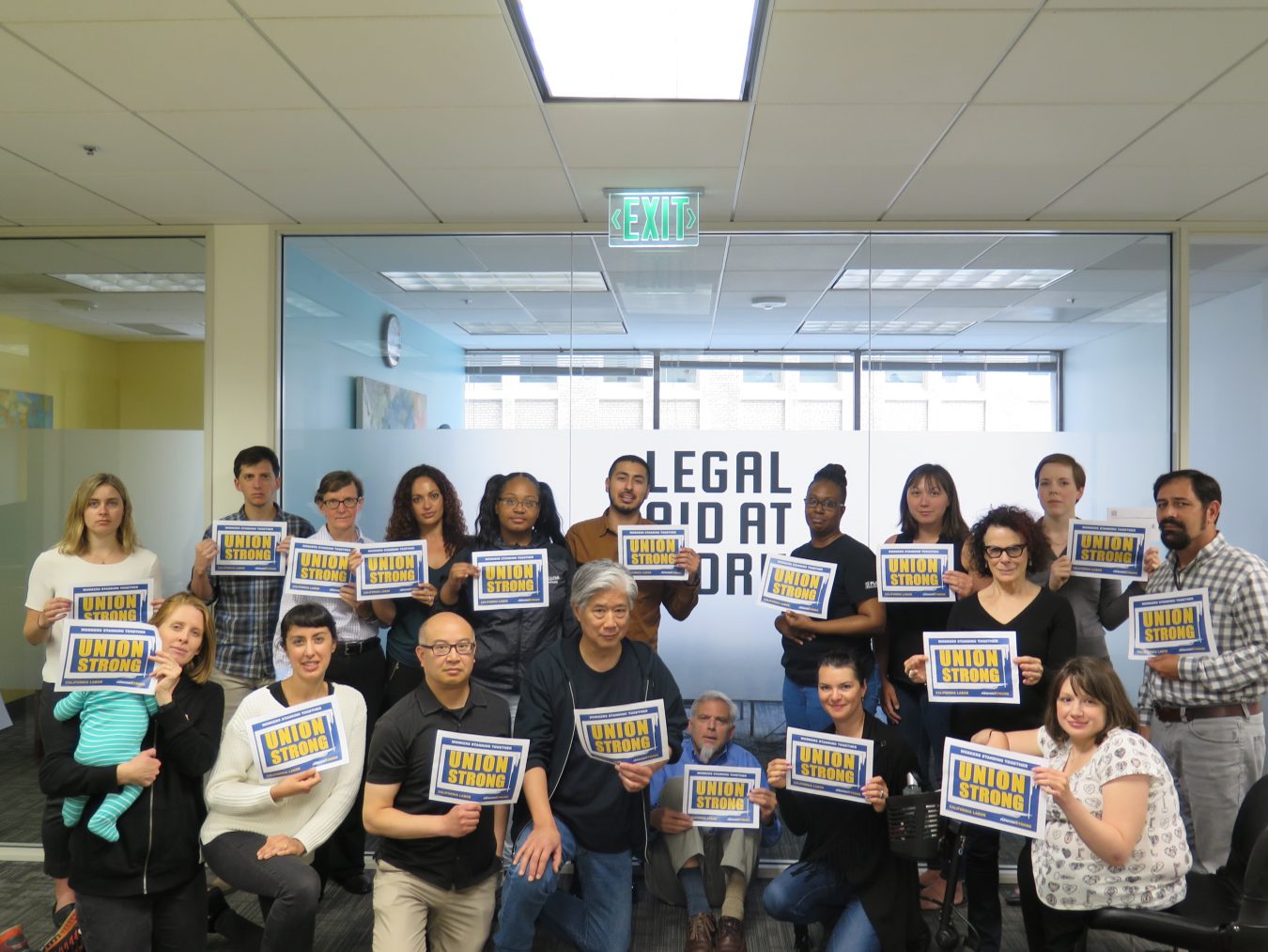 Legal Aid at Work staff members holding up "Union Strong" sign in the office