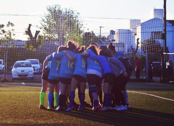 Jugadoras de fútbol acurrucadas en un partido